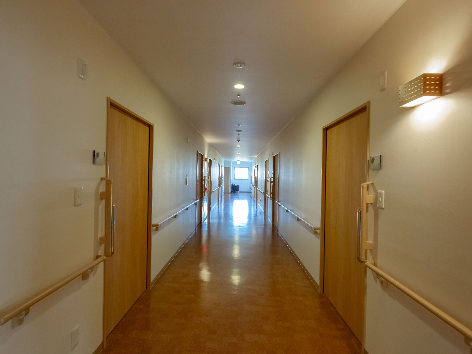 廊下の両脇に居室が並んでいる。ドアはスライド式で、つかみやすい大きな取っ手がついている。壁には手すりが設置されている。