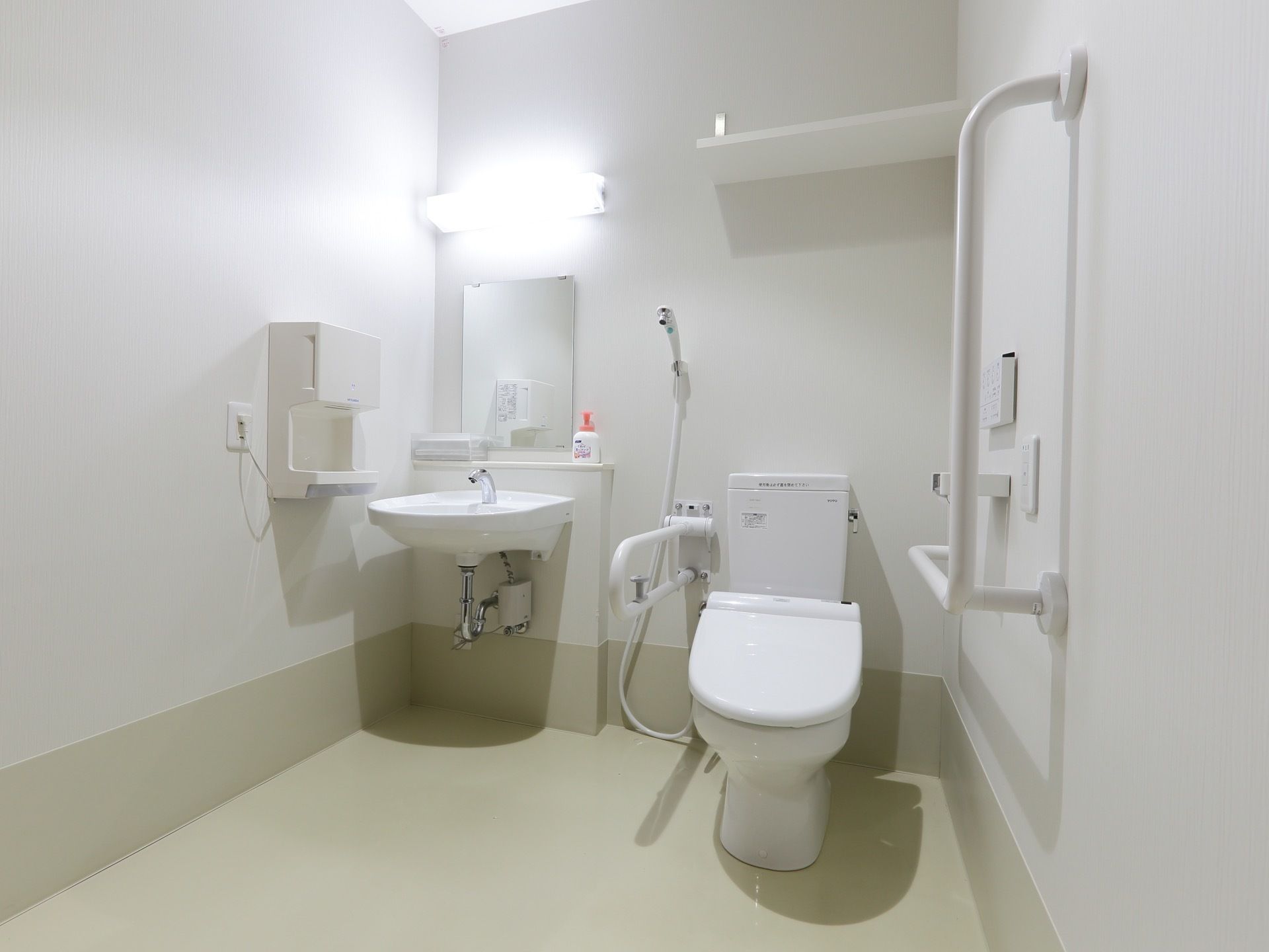 トイレには温水洗浄便座のついた、洋式便器を設置している。また壁には手すりがあり、シャワーが取り付けられている。