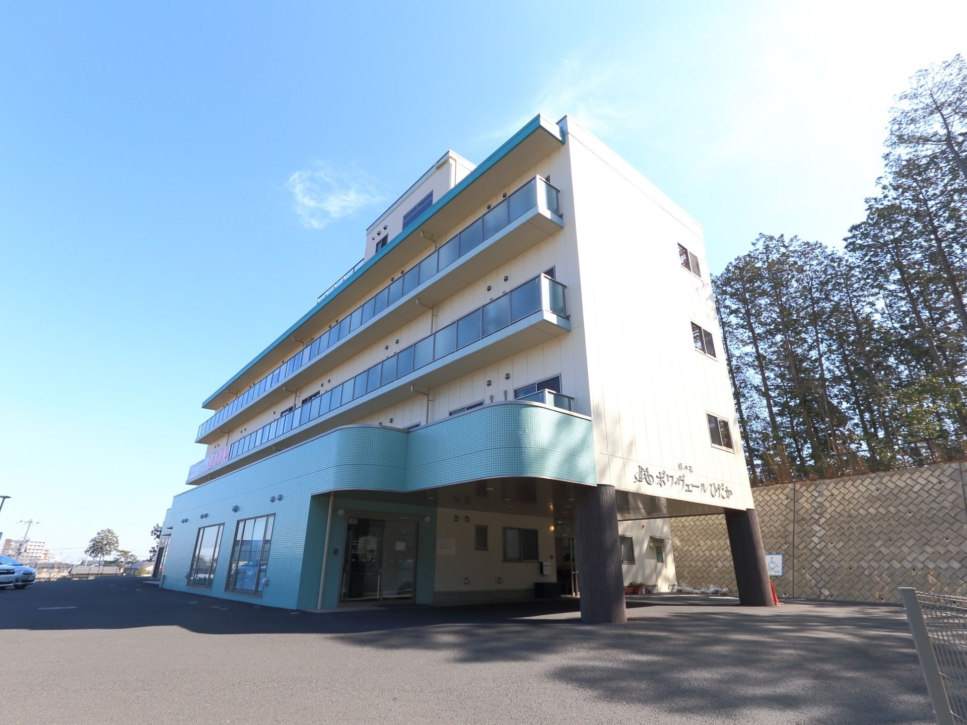 敷地内には、広々とした駐車スペースが確保されている。また施設の裏手には林があり、木々が植えられている。