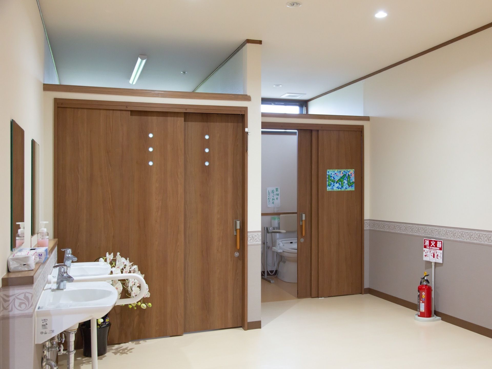 トイレの個室には、スライド式のドアを採用している。洗面所には、洗面台が２つあり、中間に掴まれるバーを設置している。
