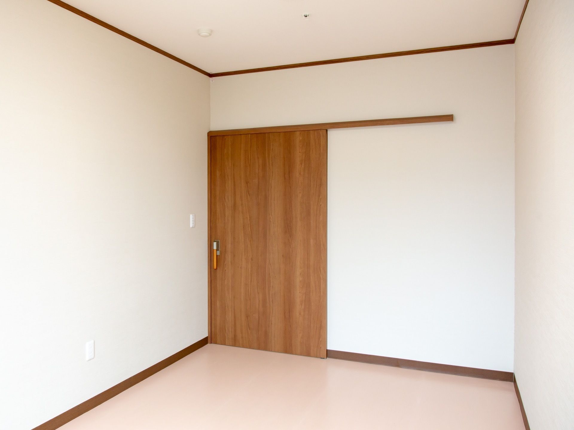 部屋のドアは、木目を活かした茶色である。車椅子をご利用の方が開け閉めしやすいよう、引き戸を採用している。