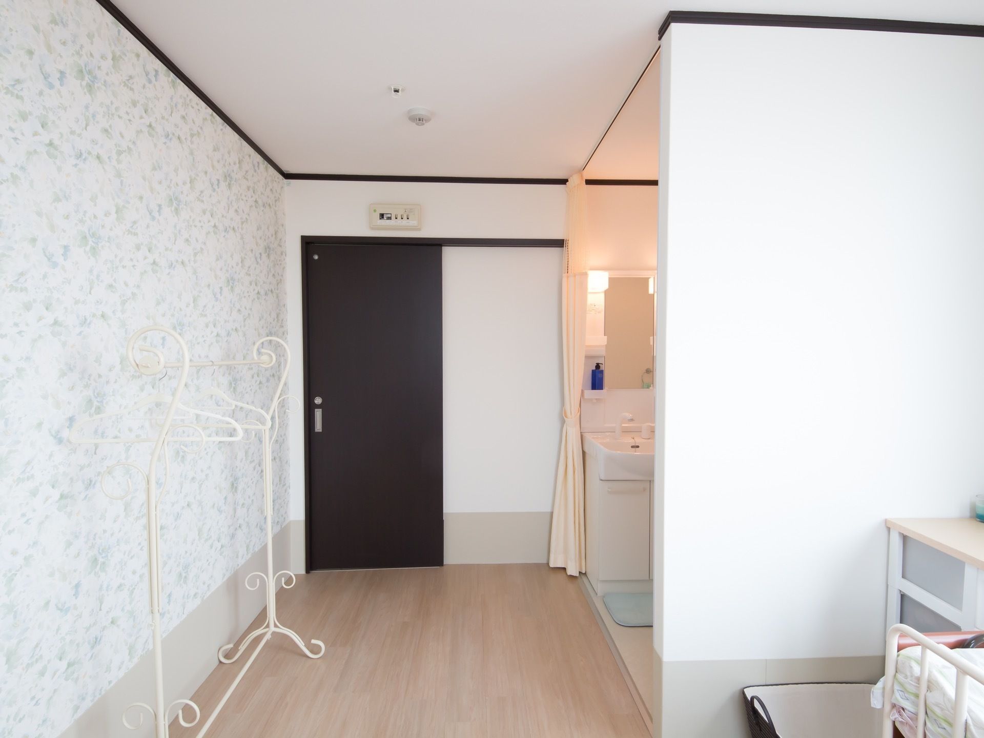 黒い扉は引き戸で、扉を開けるとすぐ洗面化粧台がある。壁際には、白いおしゃれなハンガーラックが置いてある。