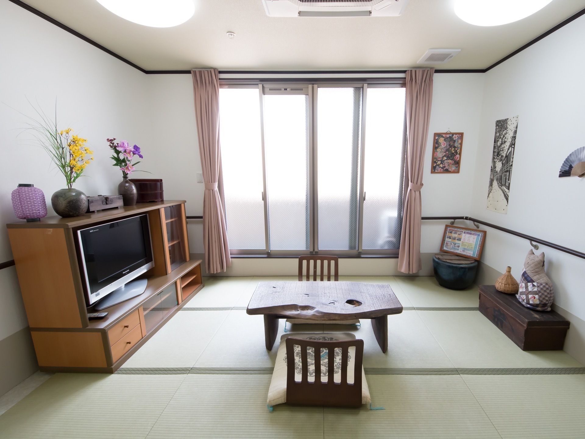 畳の居室で、中央には木でできたテーブルと座椅子が2脚置いてある。テレビはテーブルの高さに合わせたラックに収納されている。
