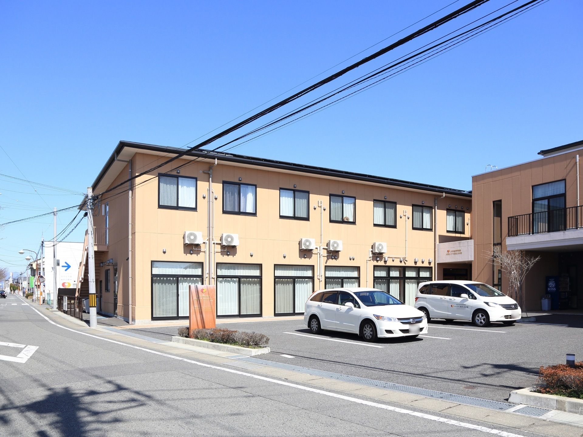 道路に面した建物である。窓が並ぶ前は駐車スペースになっていて、日当たりがよい。敷地内はアスファルトで舗装されている。