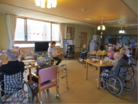食堂に集まり体を動かすレクリエーションを楽しむ居住者様