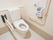 車椅子対応のトイレである、Ｌ型や可動式の手すり、ナースコールが完備されている。洋式便器後ろの壁は備品を置ける棚になっている。