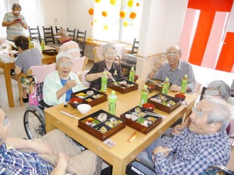 テーブルを囲んで食事を楽しむ高齢者