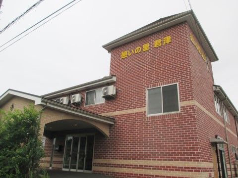 赤いレンガ造りの重厚感ある外観。玄関前は舗装され、段差がない。上にはひさしが付いている。手入れされた植栽が見える。