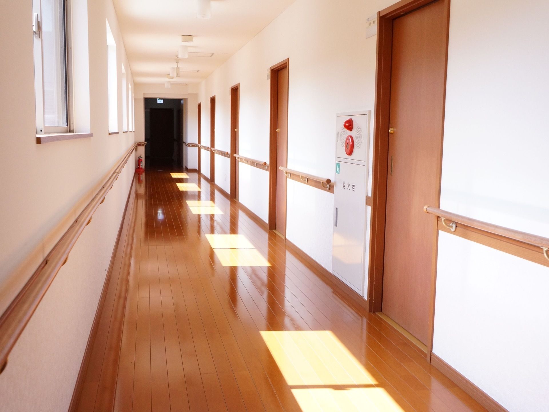 等間隔に居室のドアが設置してある。通路の両脇には手すりが設けられている。消火栓と消火器が設置してある。