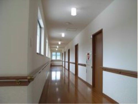 多くの窓があって明るい廊下は車椅子も楽に通れる広さがある。手すりが設置されているので安心して通行できる。