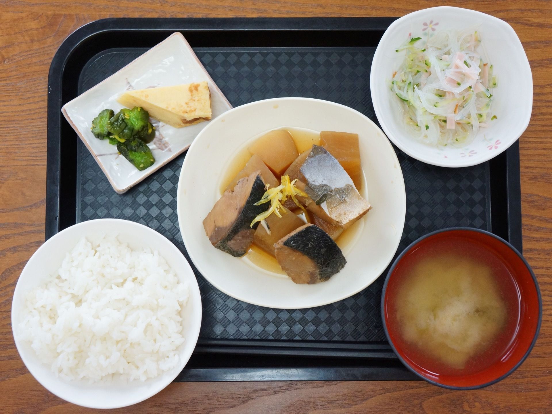 ご飯、お味噌汁、魚の煮物、サラダ、漬物のそれぞれがお皿に盛りつけられて、お箸と共にお盆の上に用意されている。