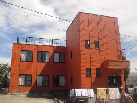 オレンジ色が印象的な外壁で、遠くからでもすぐわかる建物である。建物の前には布団や洗濯物が干されている。