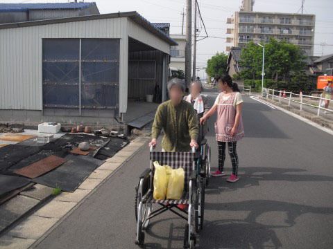 ヘルパーの女性に付き添われて外を歩く買い物帰りの居住者様