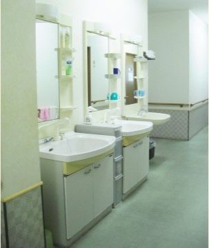 洗面台を３つ設置しており、いつでも待つことなく利用することができる。前の壁には鏡があり、身だしなみを整える際に便利である。