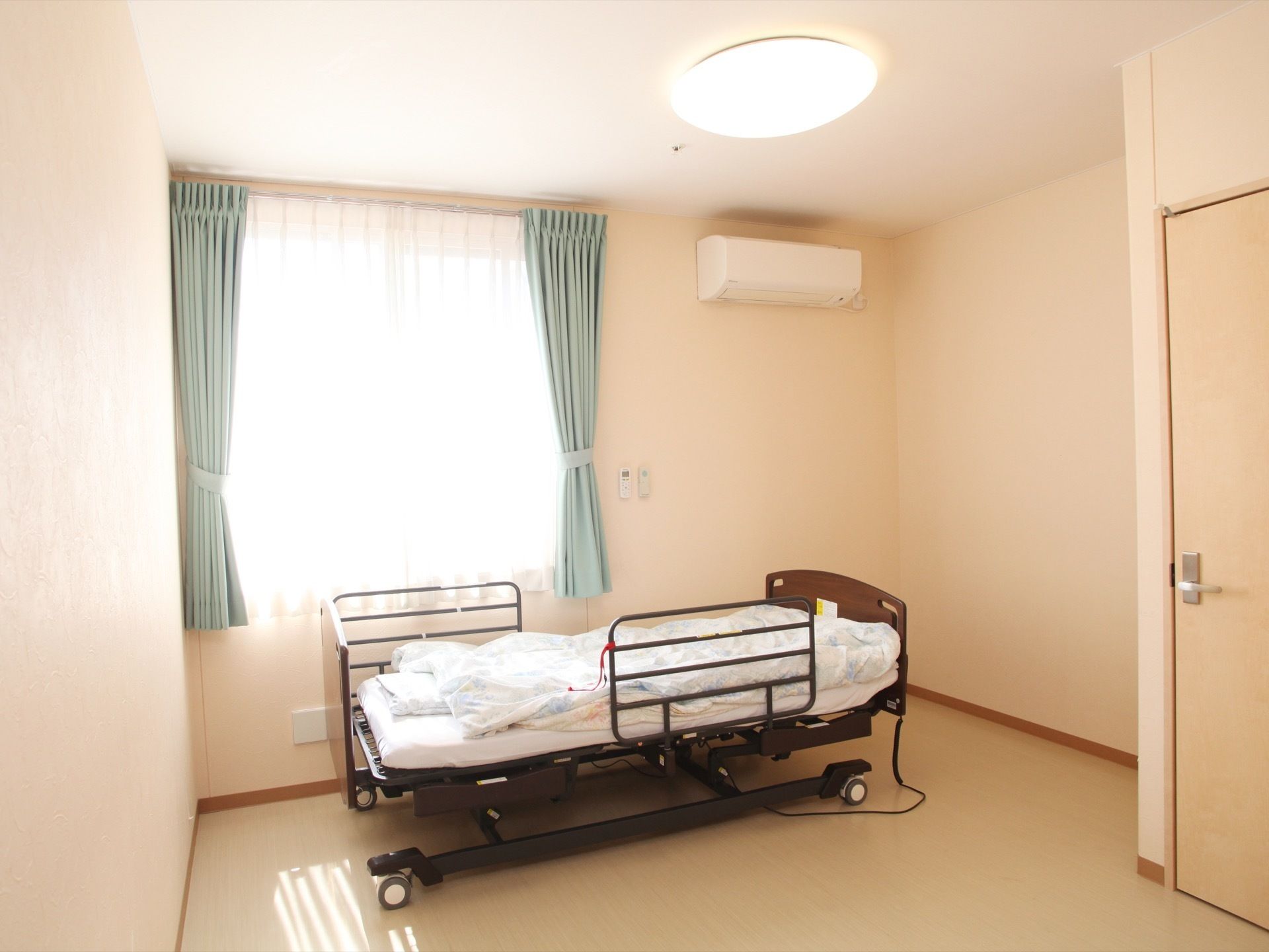個室に設置されているベッドは電動式で、横になったまま起き上がることができる。室内は窓から外の光が差し込み、明るい印象である。