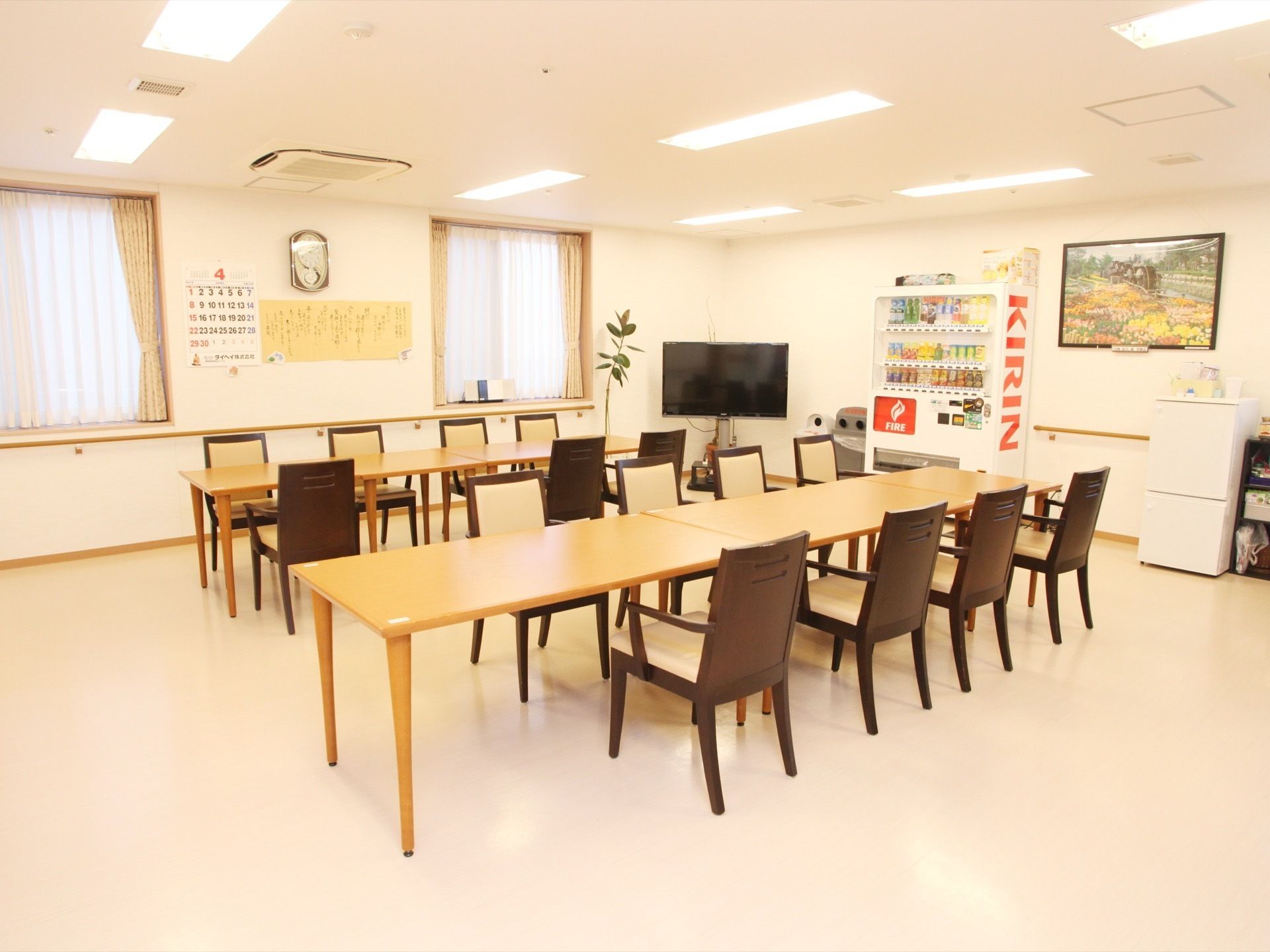 広いテーブルに椅子がたくさん並べられている。窓にはレースのカーテンが引かれている。テレビや自動販売機、小さな冷蔵庫が置かれている。