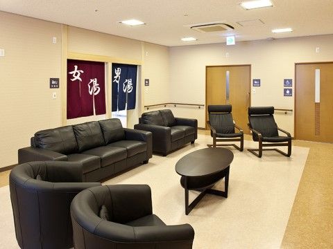 のれんが掛かった大浴場の入り口前には、広い部屋がある。中央にはソファや寝椅子が並び、トイレが２箇所ある。
