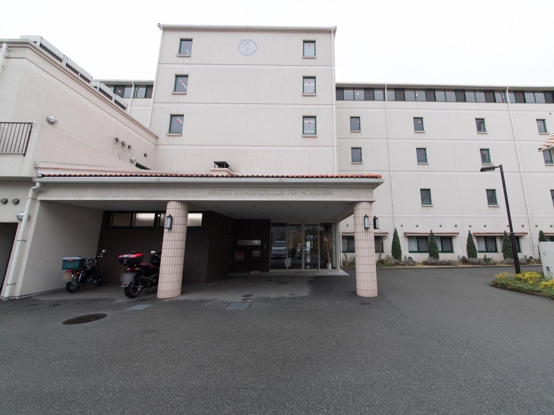 建物はピンクベージュの壁の５階建てで多くの入居者様が生活できる。入口も広く、車を前につけることもできる。