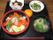 黒いお盆の上に並べられた小皿に料理が盛られている。メインがサーモンやイクラの海鮮丼で、お吸い物などもついている。