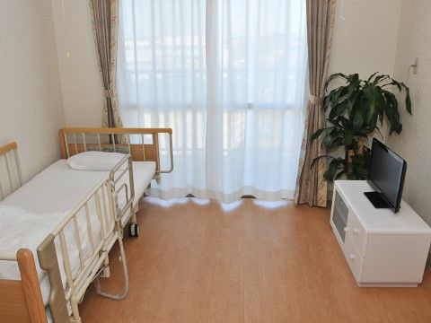 居室にはそれぞれベランダが設けられている。窓にはカーテンが掛けられている。白い台の上にテレビが置かれている。