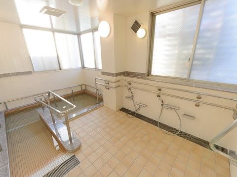 大きな浴槽には段差だけでなくスロープがあり、手すりが取り付けられているので、安全に入浴することができる。シャワーが複数設置されている。