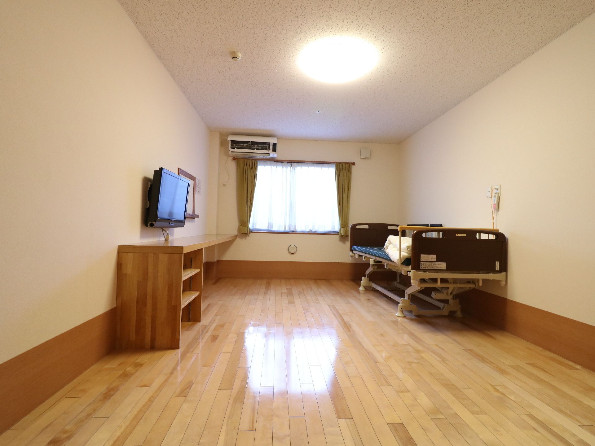 高さ調節のできるベッド、エアコン、テレビを完備した居室