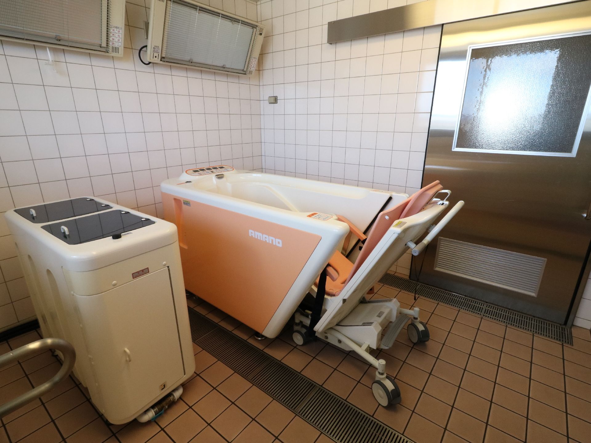 車椅子のまま入浴できる機械浴槽が設置された浴室がある。介助に必要なスペースが確保されており、壁には遠赤外線のヒーターが取付けられている。