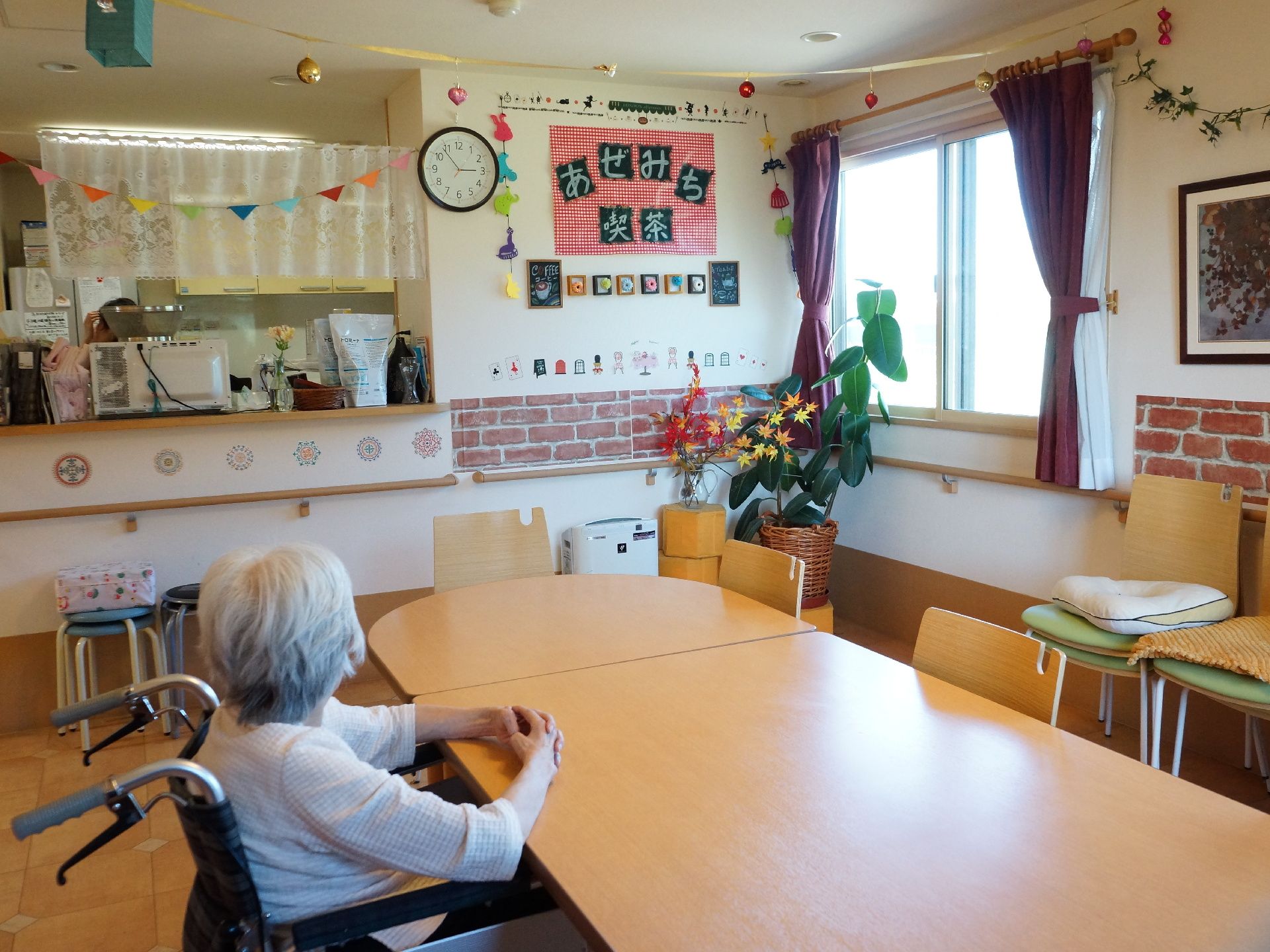 ラウンジのすぐ隣に小さなキッチンがある。壁には手すりが設けらている。手作りの作品がたくさん飾られている。