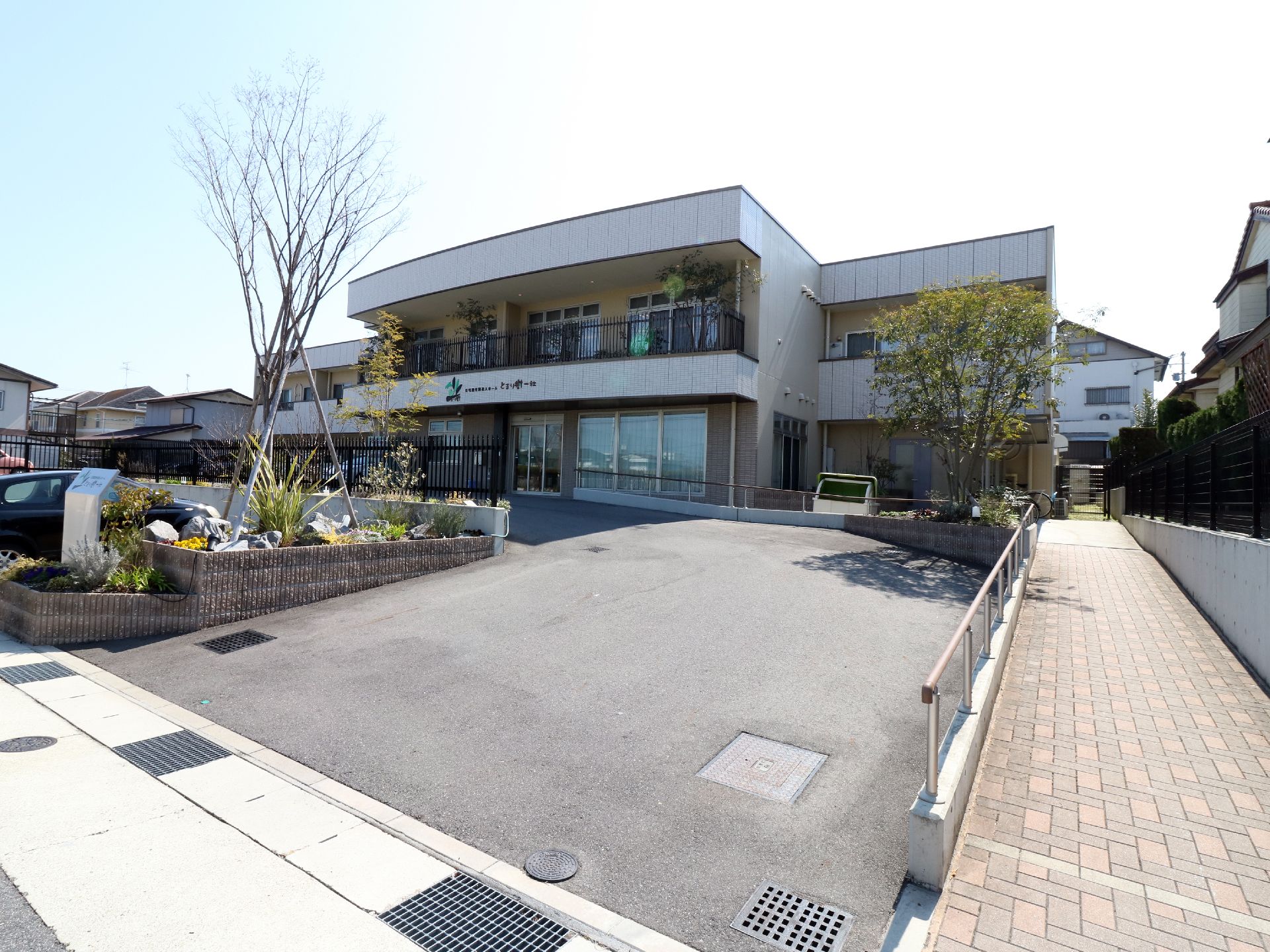 緩やかなスロープがエントランスまでつづく施設の敷地。白い外壁が清潔感を放っている。