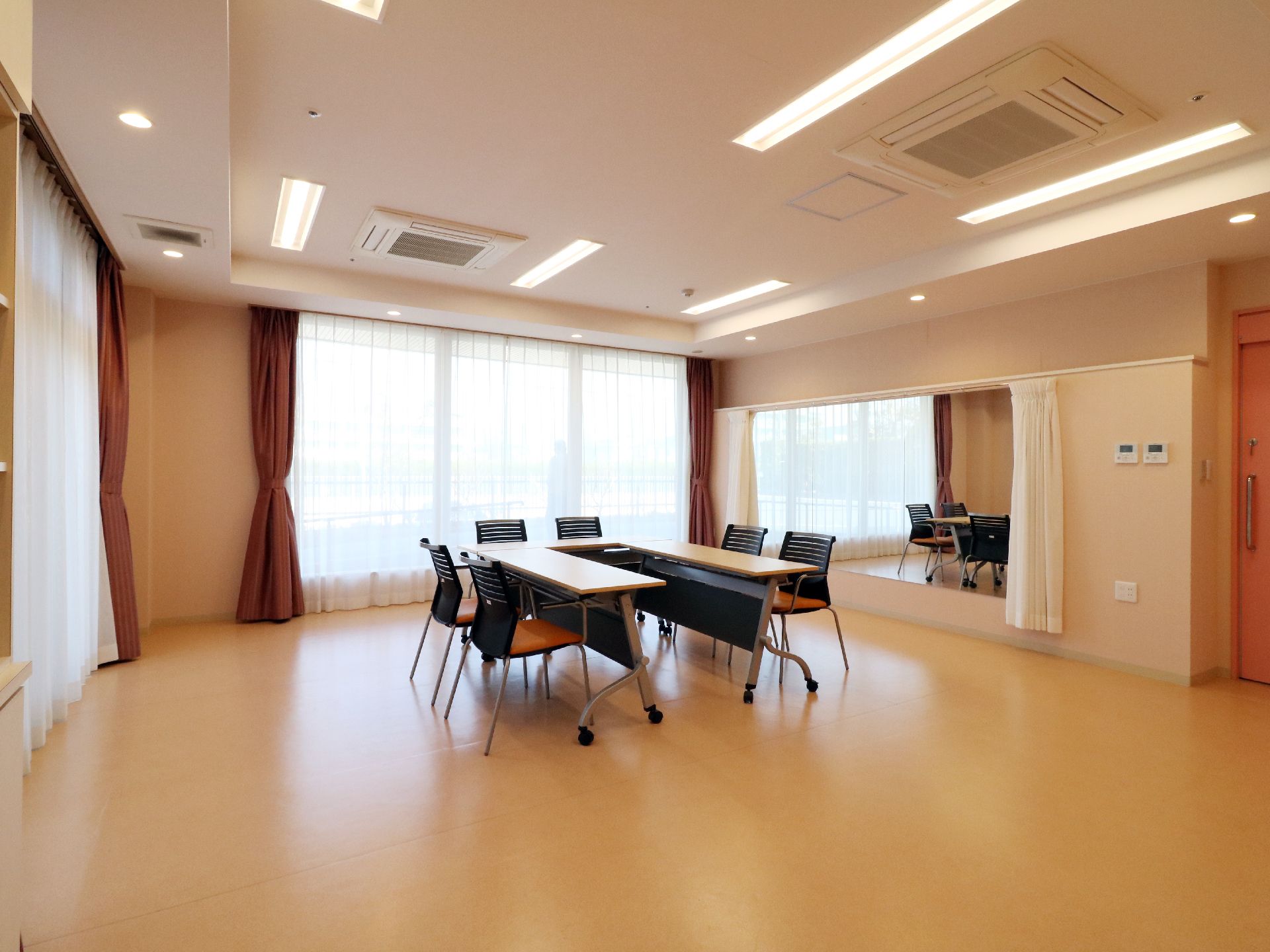 大きな窓に赤いカーテンがある。明るくきれいなフローリングの部屋。
