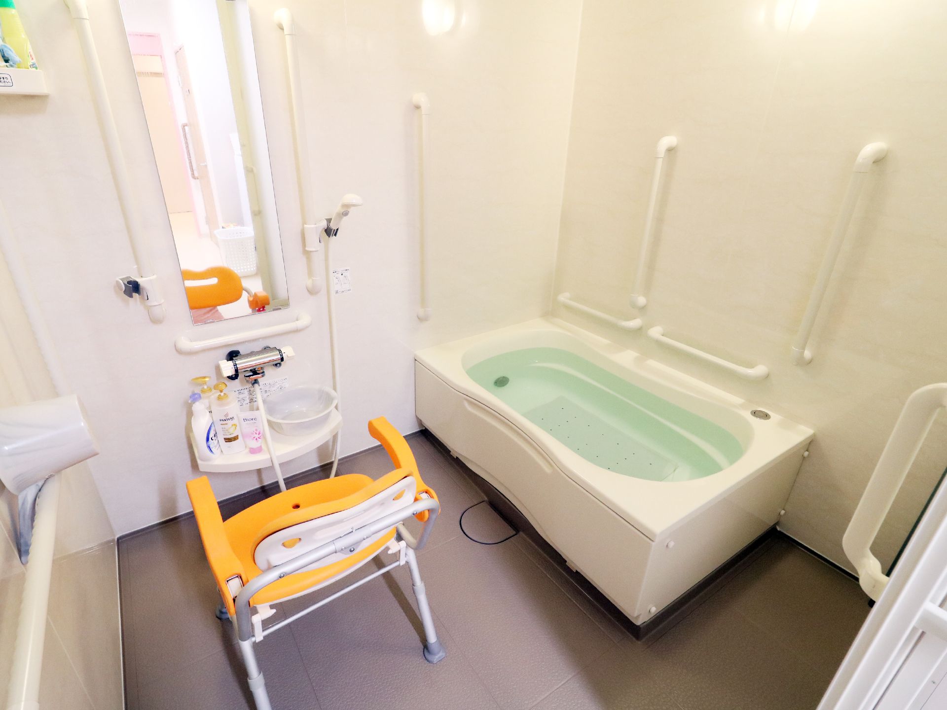 お湯の張られた浴槽。黄色い介助椅子がある。
