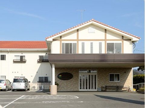 屋根のあるエントランスは広々としていて、ベンチが設置されている。建物の前には広い駐車場も完備されている。