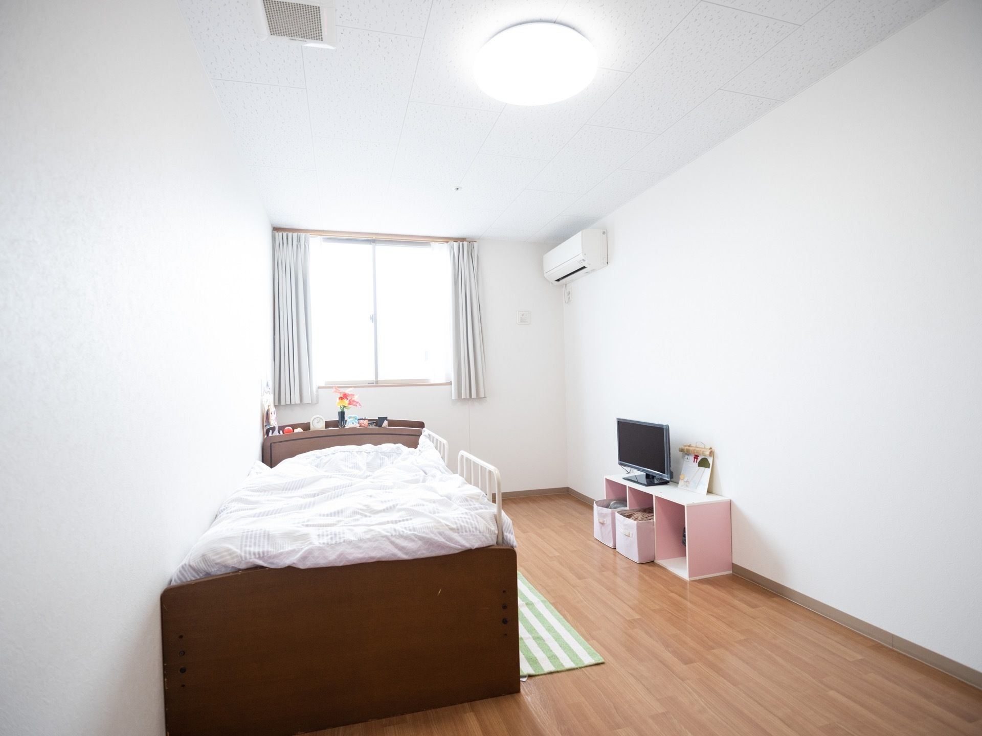 床がフローリングの洋室タイプの長方形の部屋である。ベッドには柵が取り付けられており、枕元には時計が置いてある。