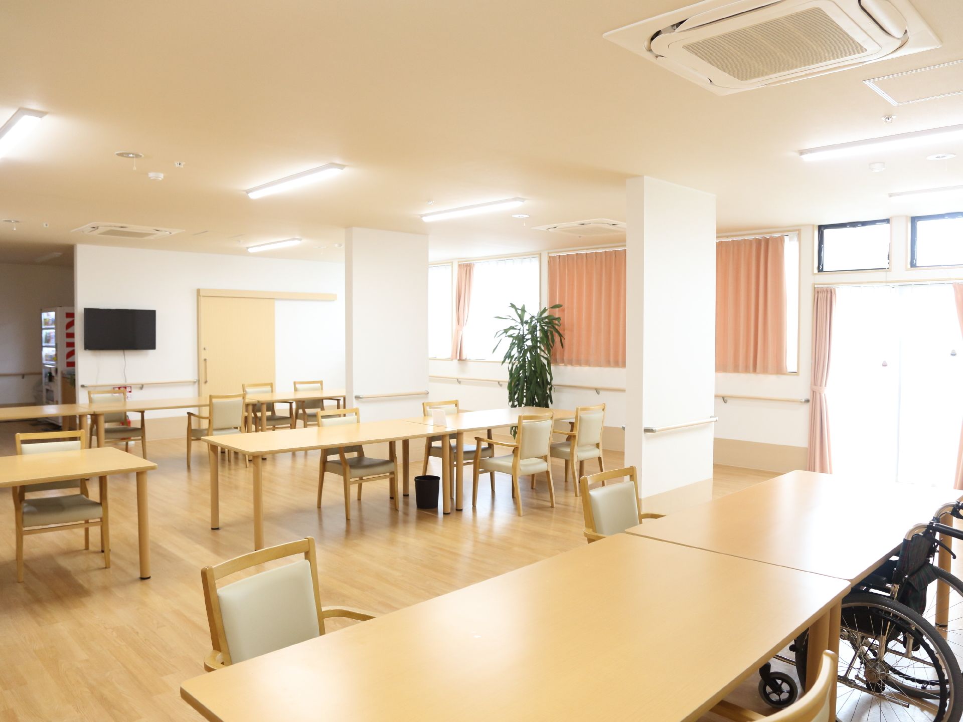 大変明るい食堂には複数のテーブルが間隔に余裕をもって配置されている。奥には自動販売機も設置されている。