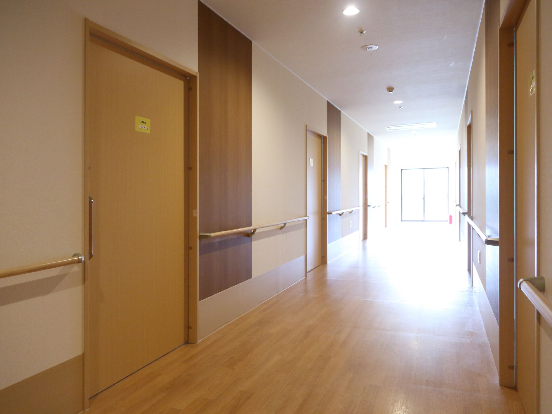 広くて明るい廊下の左右には居室が並んでいる。居室の扉は引き戸になっていて、車椅子での出入りもしやすい。