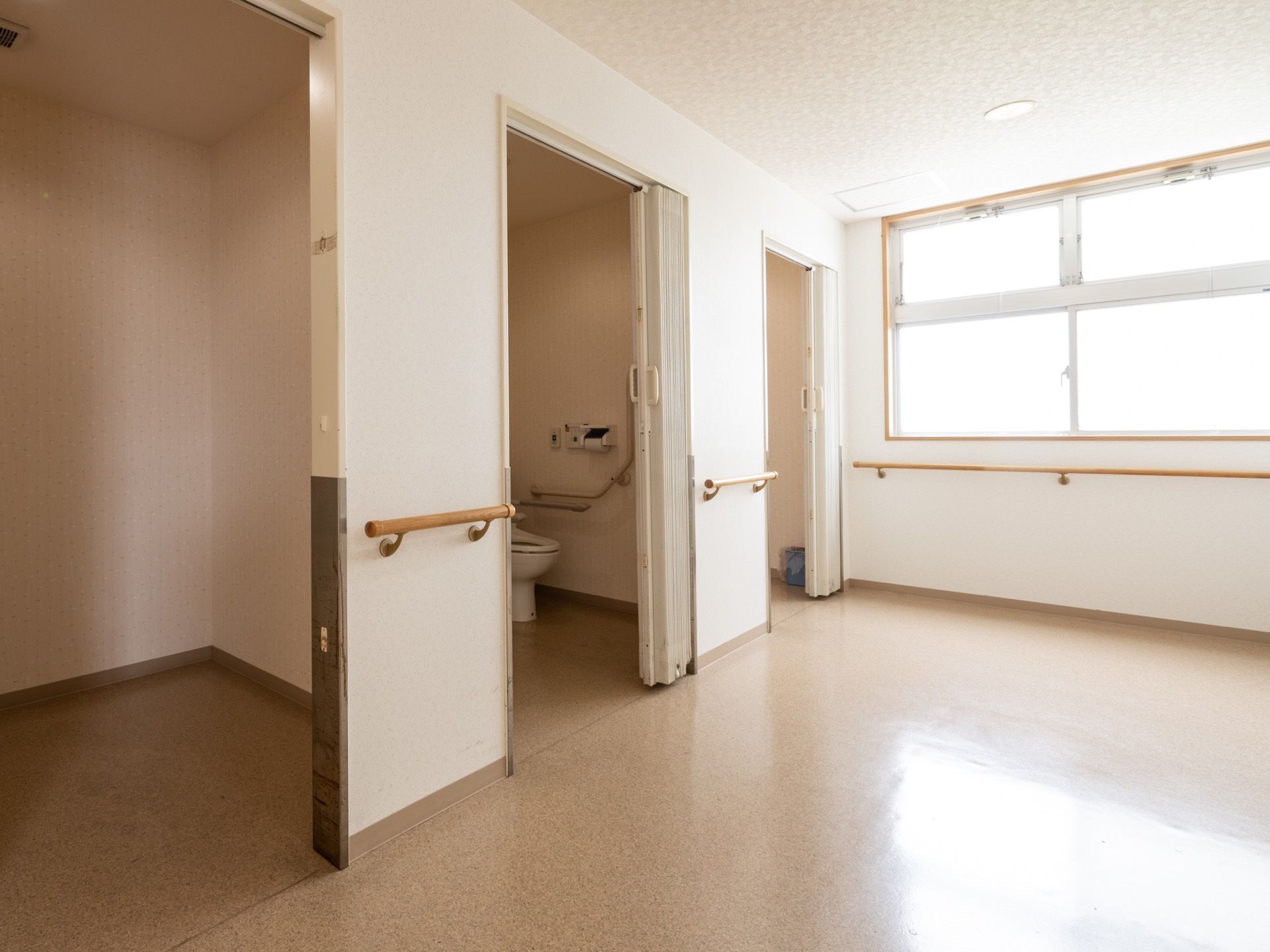 スライド式のドアのついた共有トイレが、2か所ある。通路やトイレ内の壁には手すりが取りつけられている。