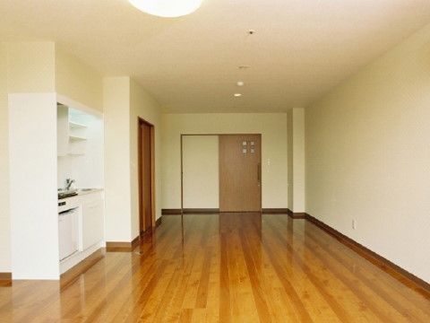 ブラウンとオフホワイトの内装の広々とした居室。キッチンと冷蔵庫が完備されているので、入居者様には料理を楽しんでいただくこともできる。