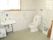 広くスペースが確保され、窓が完備されたトイレは明るい。洗面台や手すりが設置されており清潔で安全である。