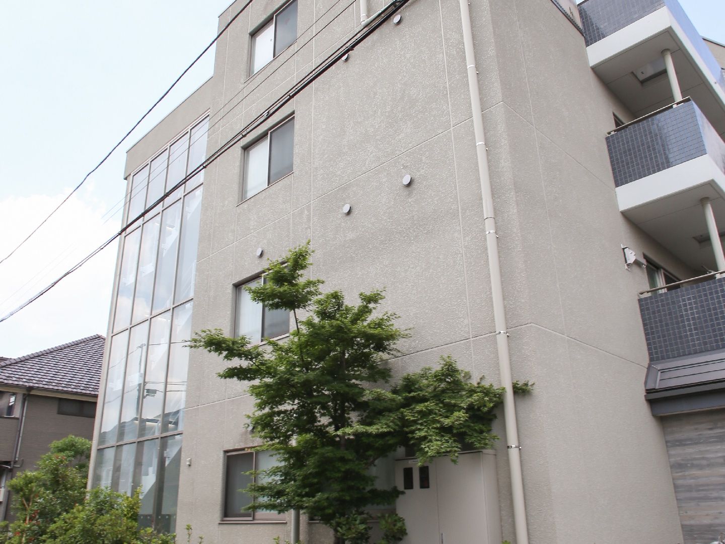 周りを緑の樹木に囲まれた、4階建ての施設。日当たりの良い方角に大きな窓がついている。階段下が駐輪場になっている。