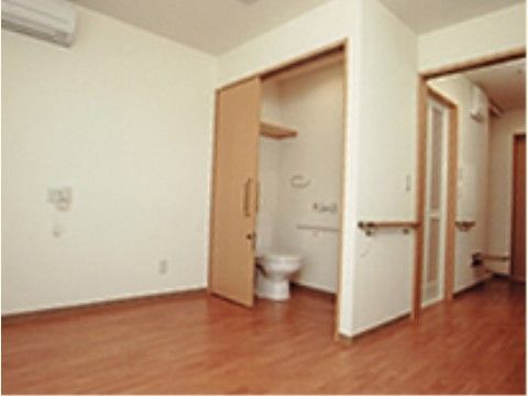 居室入口から室内にあるトイレまで手すりが取り付けられている。壁にはエアコンやコンセントの差し込み口が設置されている。