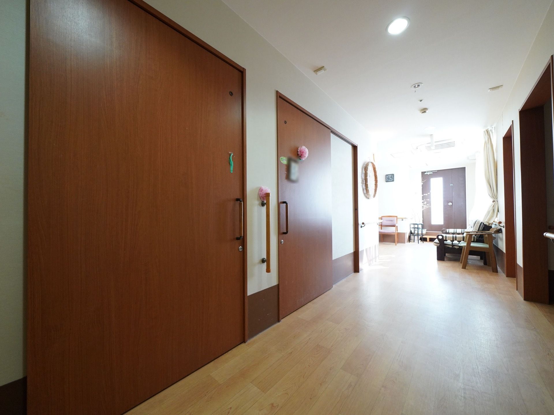 幅の広いフローリングの廊下である。居室入口の扉は、大きな木目の引き戸になっており、飾りがつけられている。