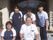 施設の玄関の前で、５人のスタッフが二列に並んでいる。役割によって、種類の違うユニフォームを着ている。