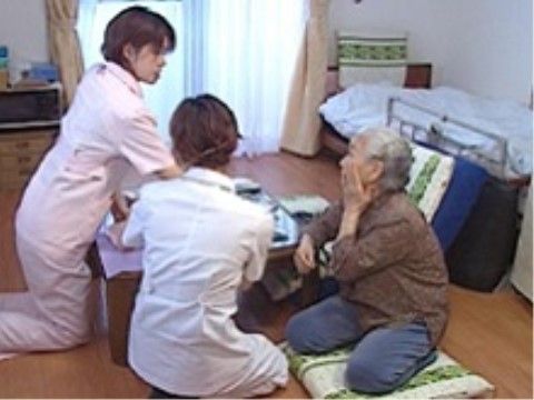 居室内で座りながら会話している、入居者と2人のスタッフ