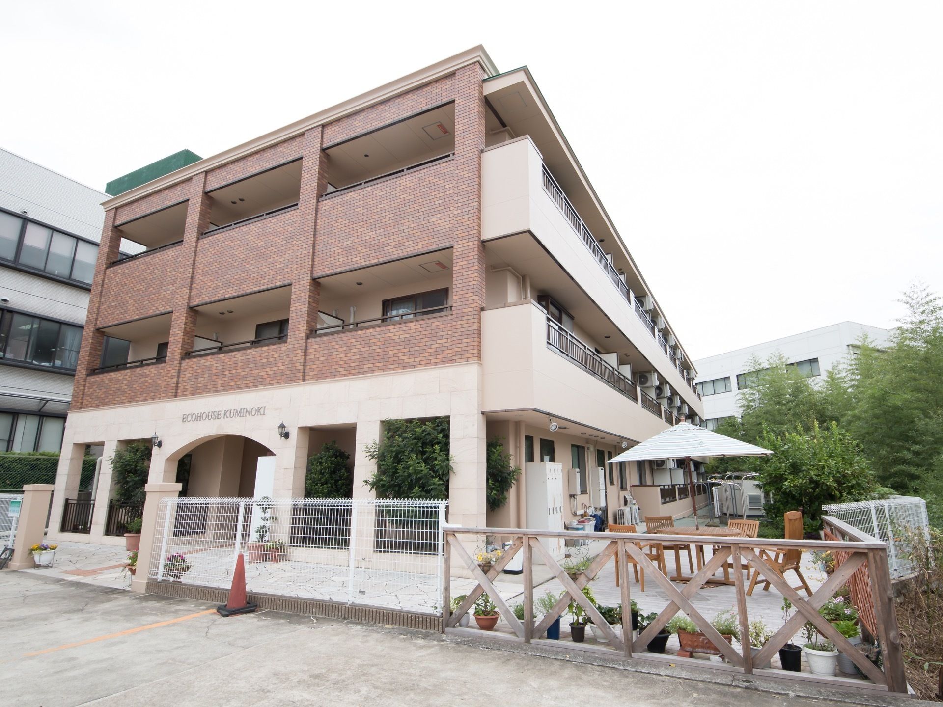落ち着きのある茶ベースの３階建て施設の外観。各居室には広々とした日当たりの良いバルコニーが設置されている。
