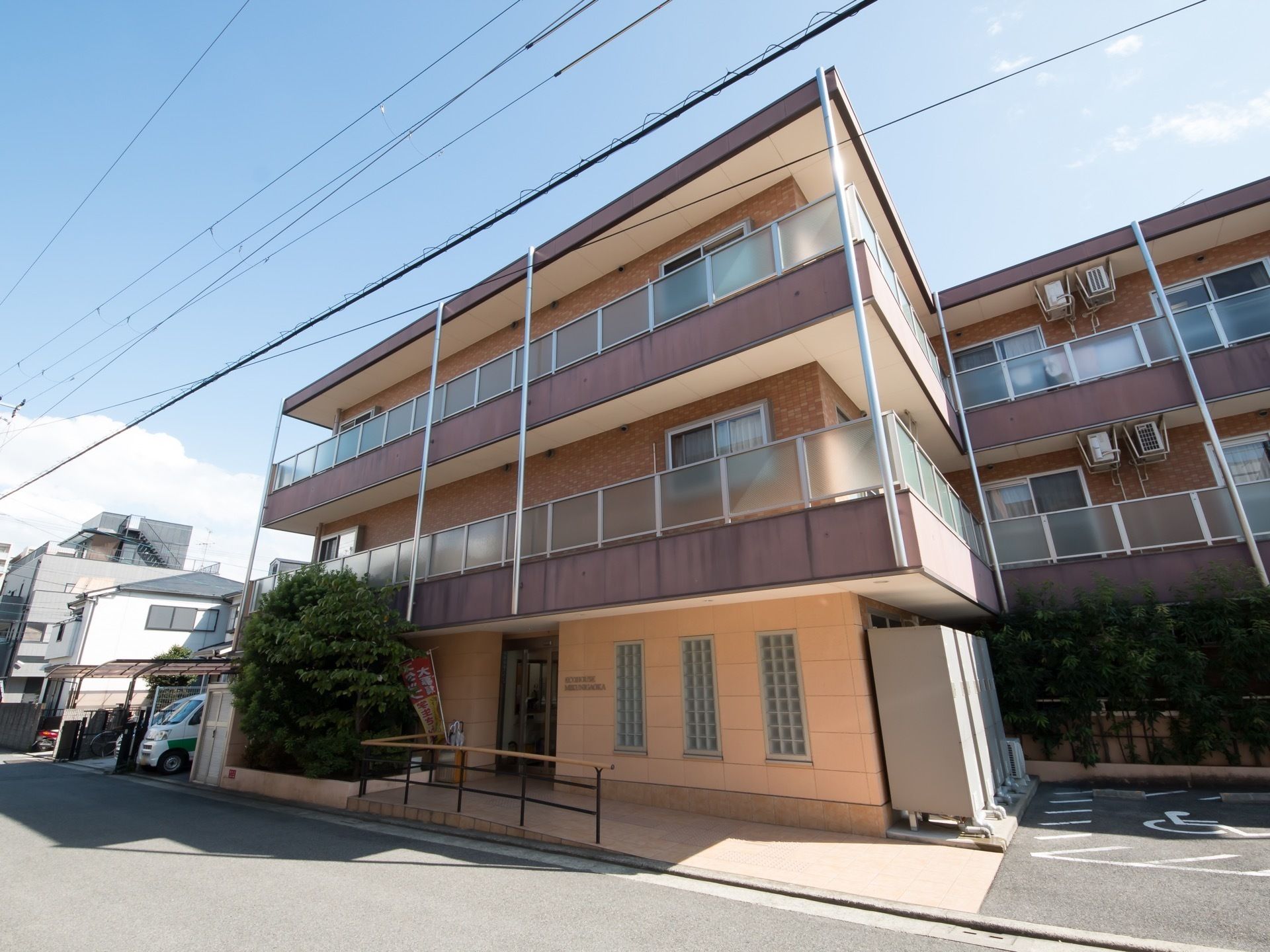 手すり付きのスロープが玄関まで配置された三階建てのホーム