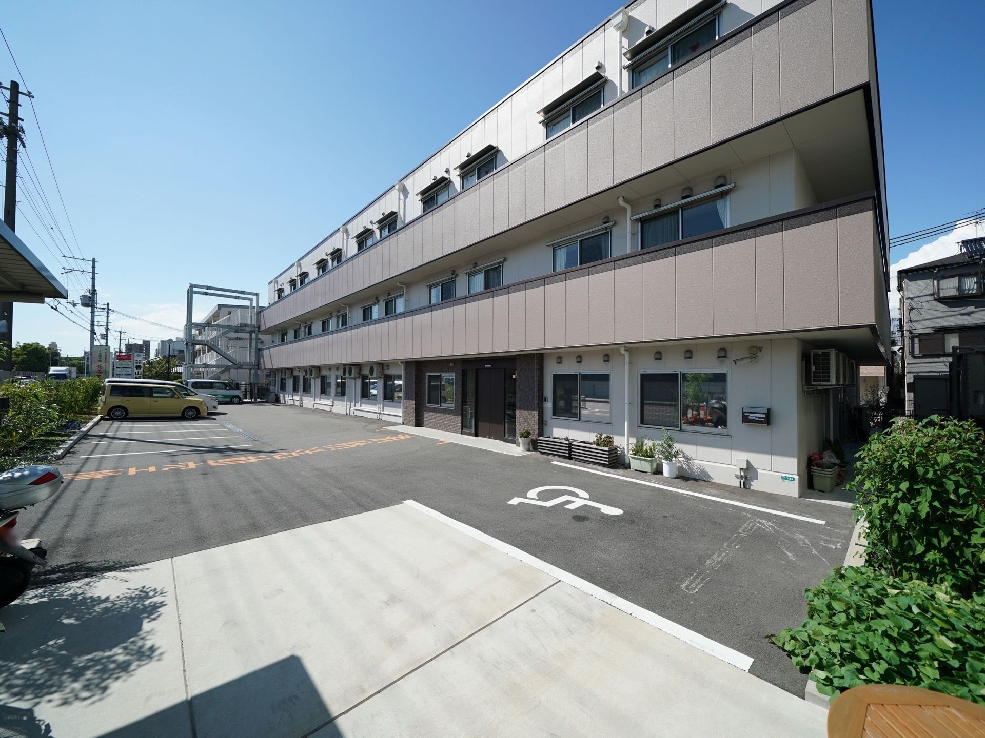 施設は、ブラウンが基調の３階建ての建物である。前には駐車場があり、車椅子をご利用の方専用のスペースを備えている。