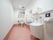 奥行のあるトイレである。便器の両脇に手すりが取りつけられている。手前に洗面台とオストメイト用の器具が設置されている。