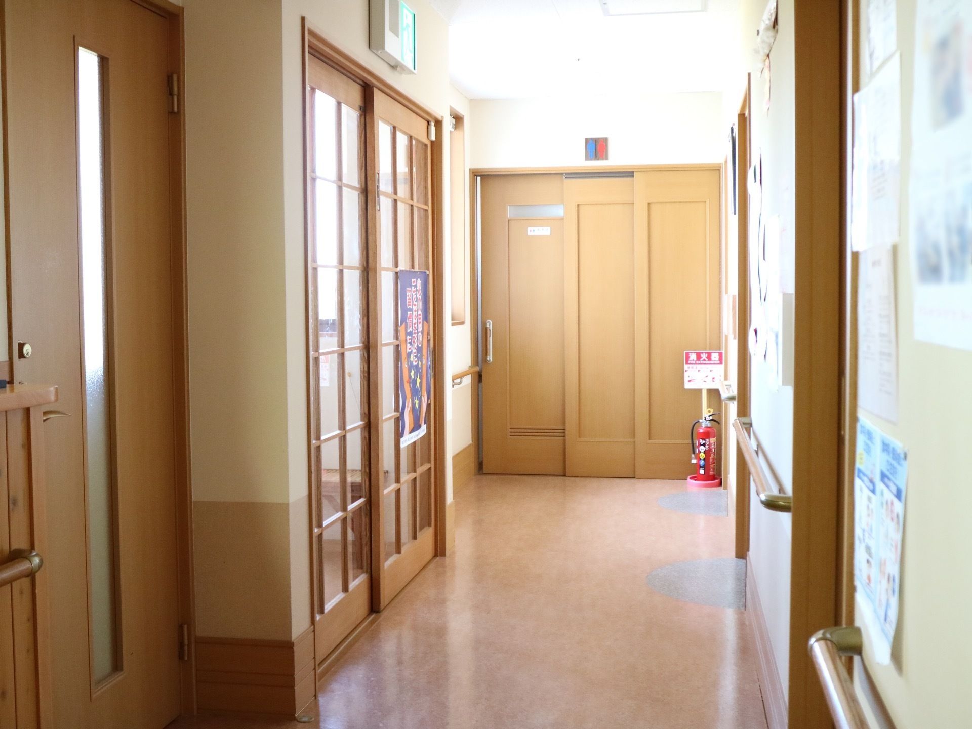 廊下の突き当りにドアがあり、閉めたままになっている。左手前にガラスの窓が嵌められた入り口ドアが見えている。
