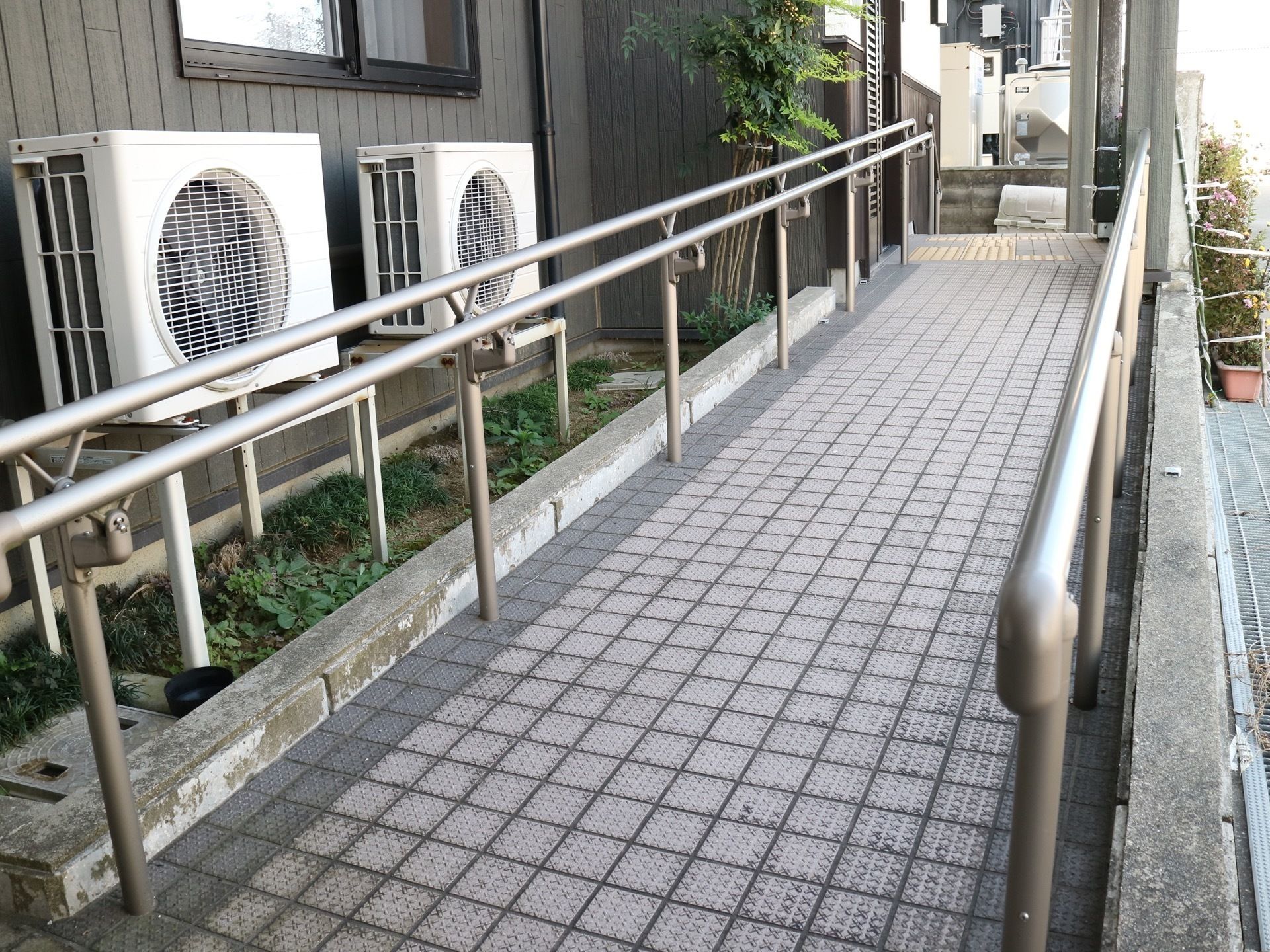 玄関アプローチに設置された緩やかな手すり付きスロープ
