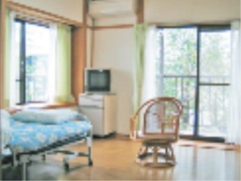 2ヶ所ある窓にはカーテンが2重にかけられ、一方は出窓になっている。ベッドと椅子が一つずつ置かれ、壁にエアコンが設置されている。